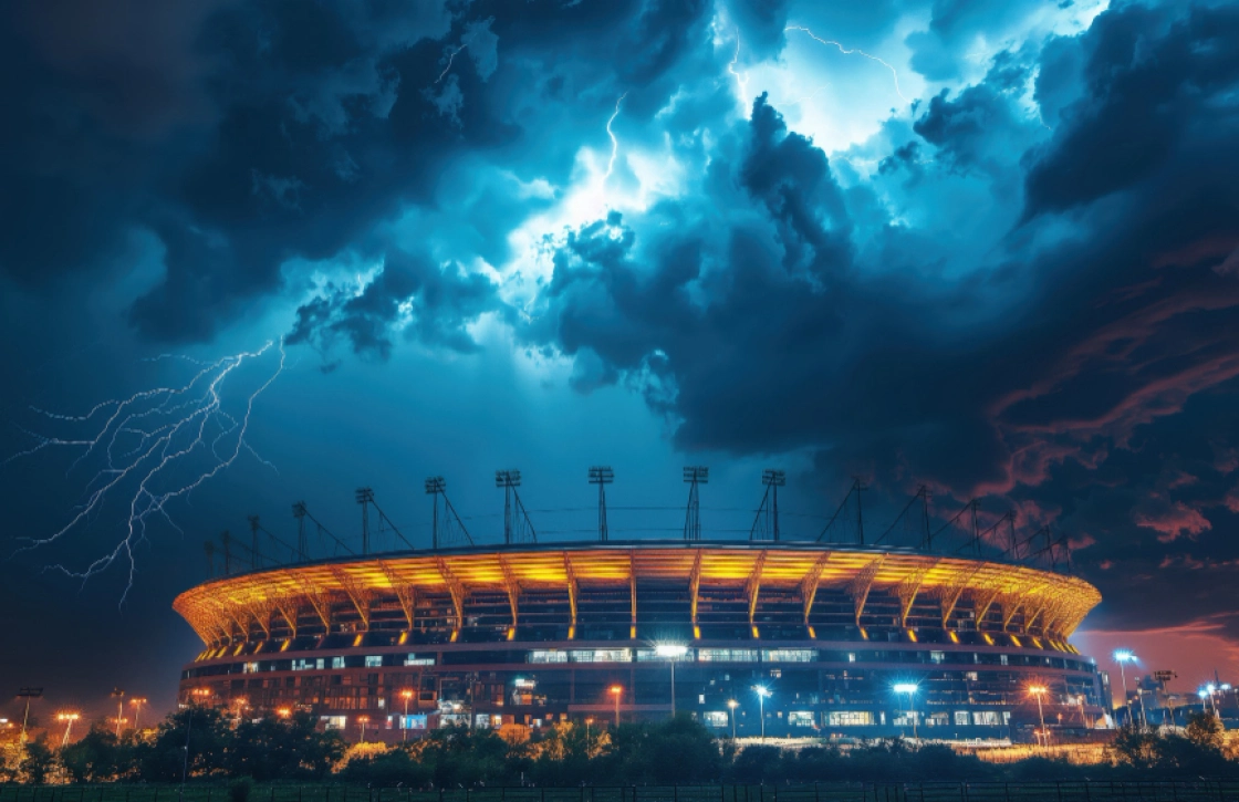 Football stadium under dramatic stormy weather with lightning in the sky.